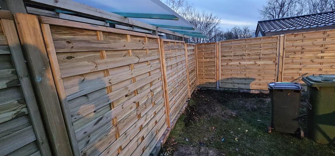 Neuer Holz-Sichtschutzzaun aus Flechtzaun-Elementen entlang der Grundstücksgrenze