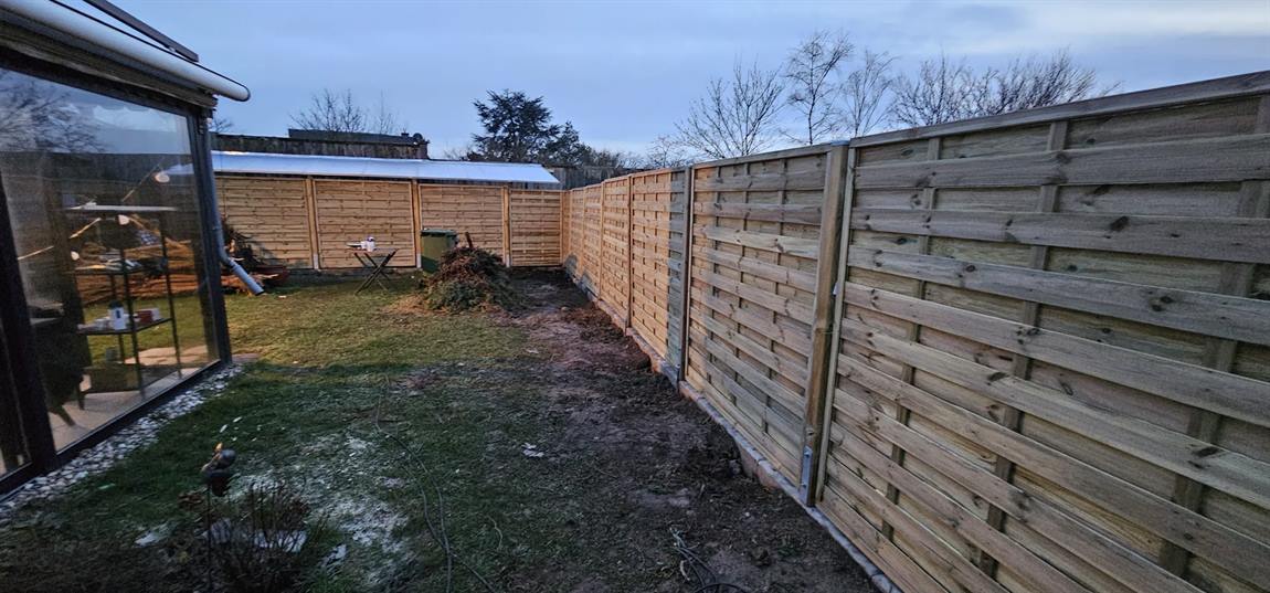 Holzzaun um einen Garten, Blick vom Wintergarten aus